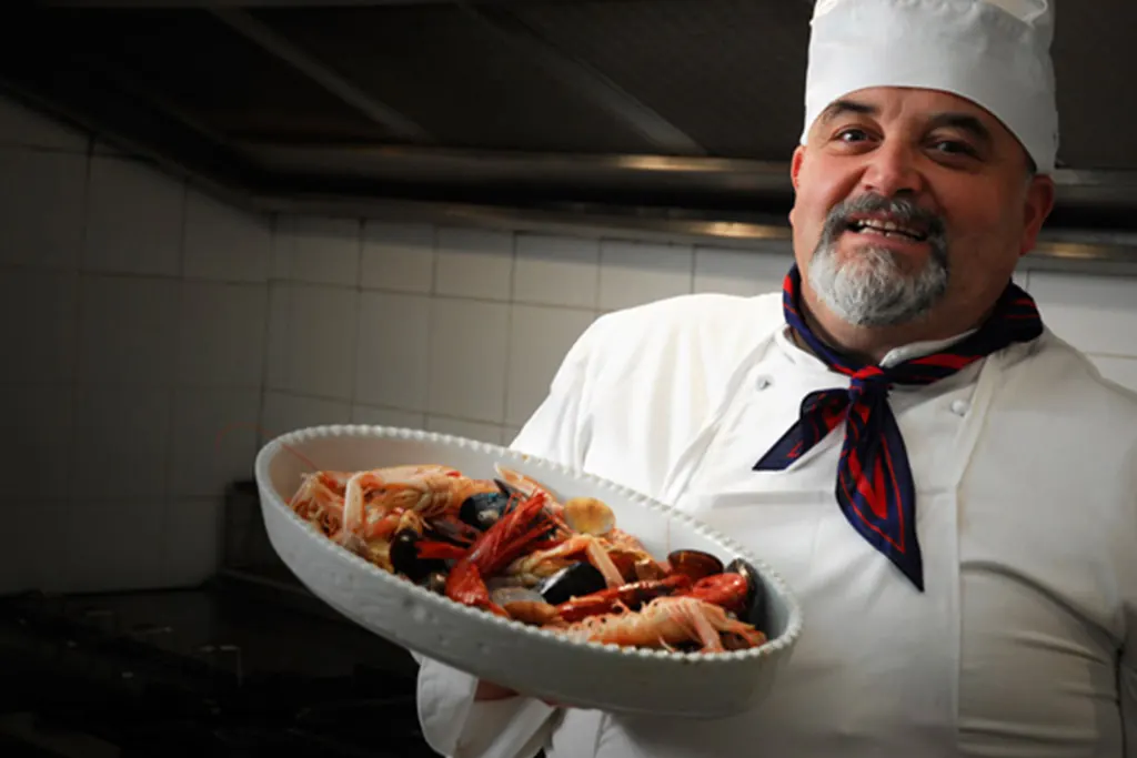 Lo chef con un piatto di pasta ai frutti di mare